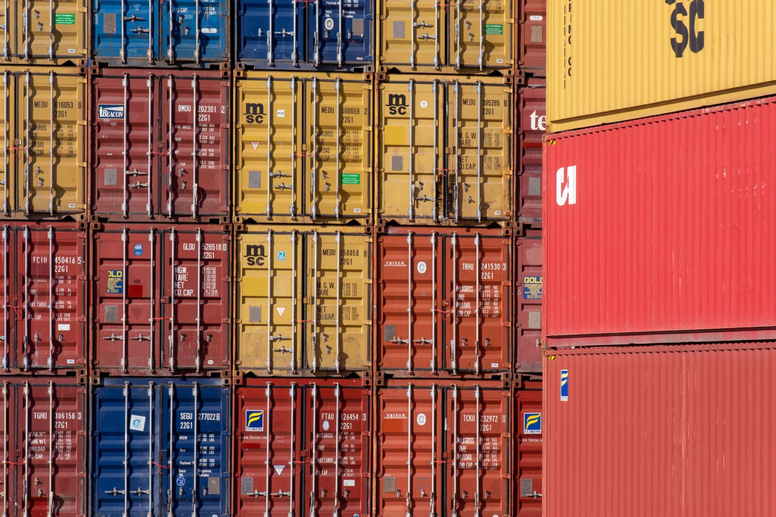 Red, yellow and blue shipping containers stacked in rows.